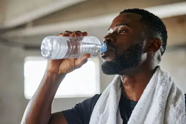 Image of man drinking water to improve hydration Sevenoaks after work out.